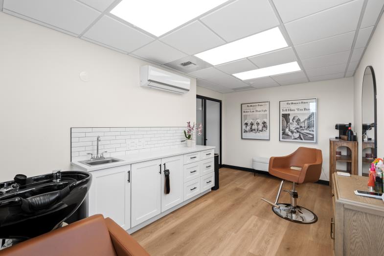 Salon suite interior with a black shampoo basin, white cabinets and an orange styling chair